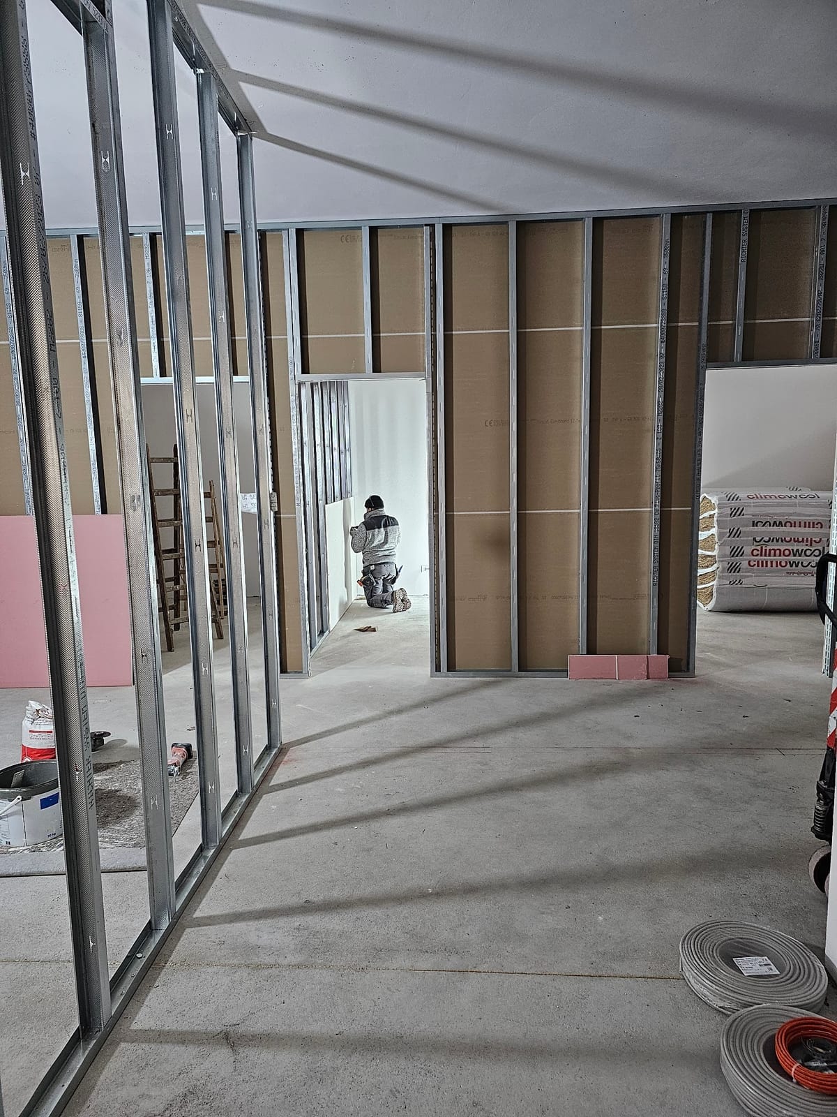 Durchlaufendes CW-Ständerwerk auf einer großen Trockenbaubaustelle, Dämmpakete gestapelt